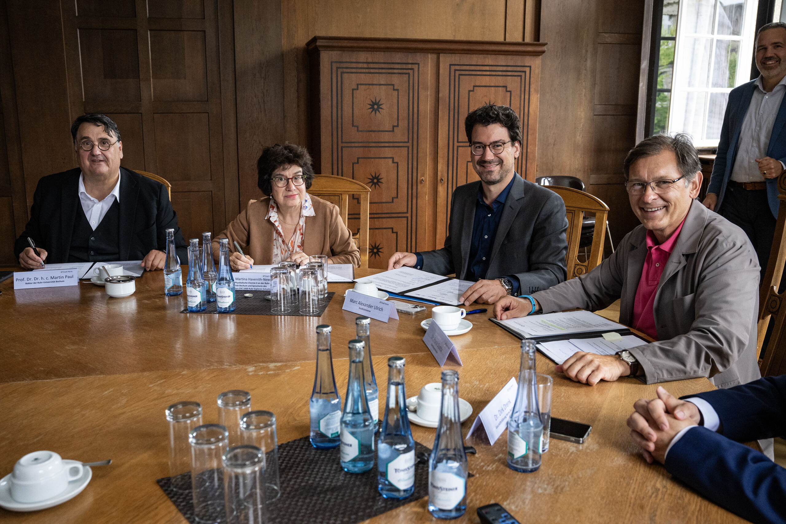 Personen sitzen an einem Tisch im Herner Rathaus und unterzeichnen eine Absichtserklärung. Auf dem Foto zu sehen sind seitens der RUB Prof. Dr. Dr. h. c. Martin Paul und Prof. Dr. Martina Havenith-Newen sowie seitens der Stadt Herne Stadtkämmerer Marc Alexander Ulrich und Oberbürgermeister Dr. Frank Dudda.